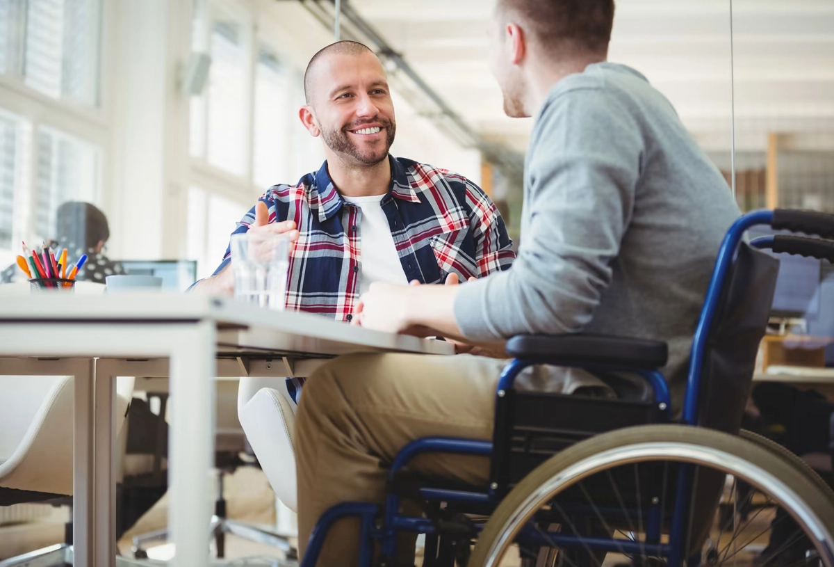 man smiling with another man in a wheelchair